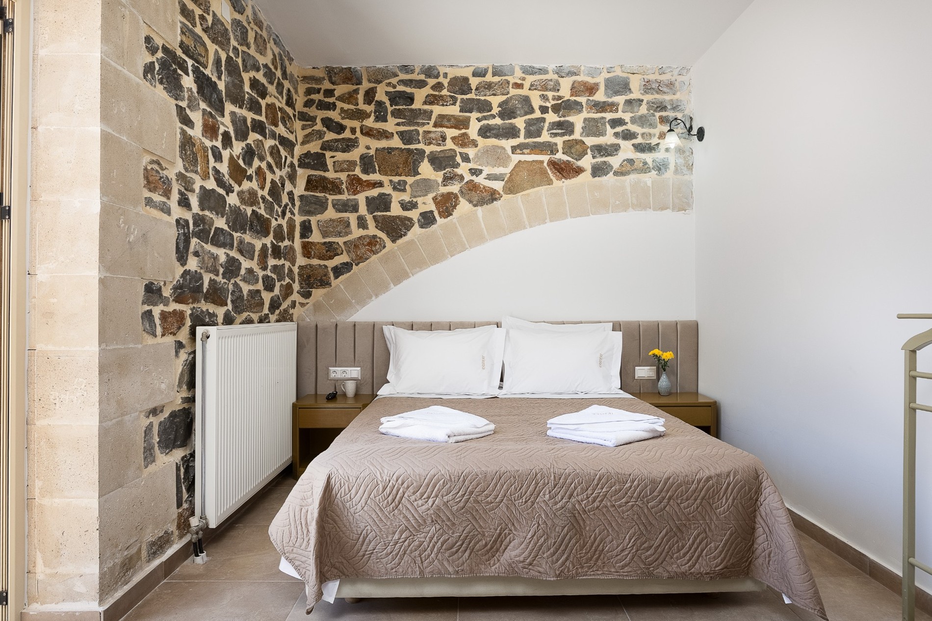 Double bedroom beneath an exposed stone arch